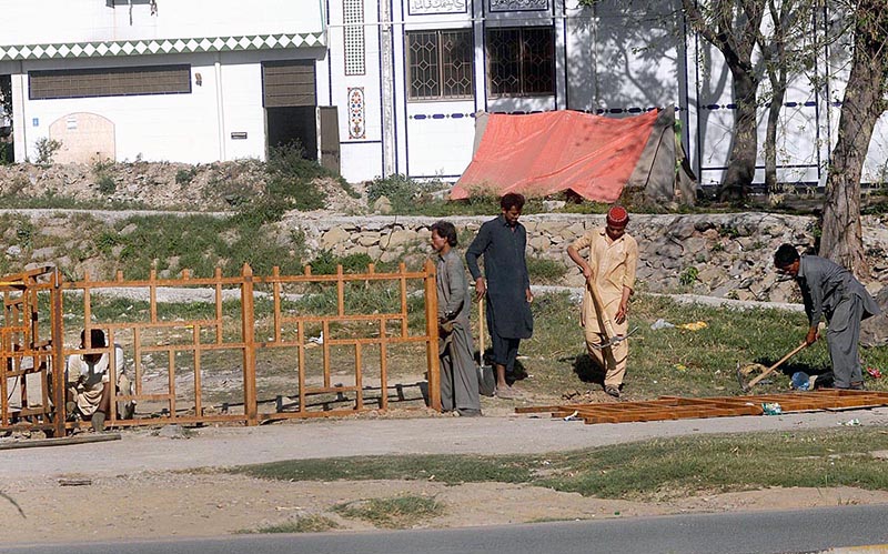 Laborers are installing iron fence on the edge of a CDA park on Khushal Khatak Road in a Federal Capital