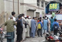 People standing in a queue to purchase flour bags from delivery truck on subsidy rate by the government at Lakshmi Chowk