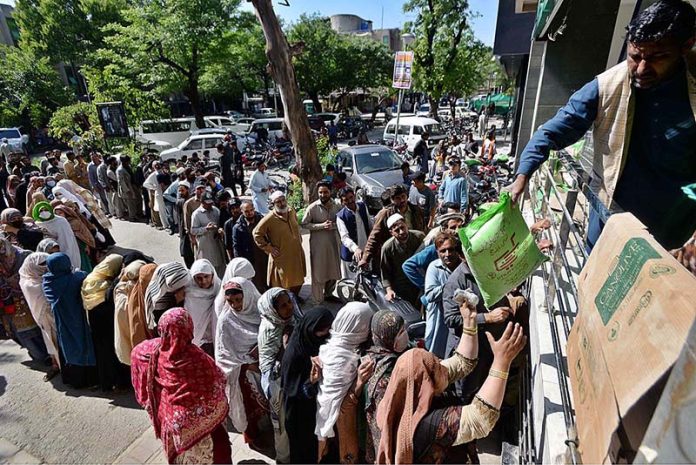 People standing in a queue for purchasing 10kg flour bags outside the utility store at Sitara Market