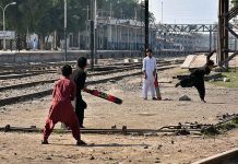 Children playing cricket near railway tracks which may lead to an accident