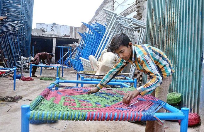 A young workers are knitting the traditional bed (Charpai) for customers at their workplace