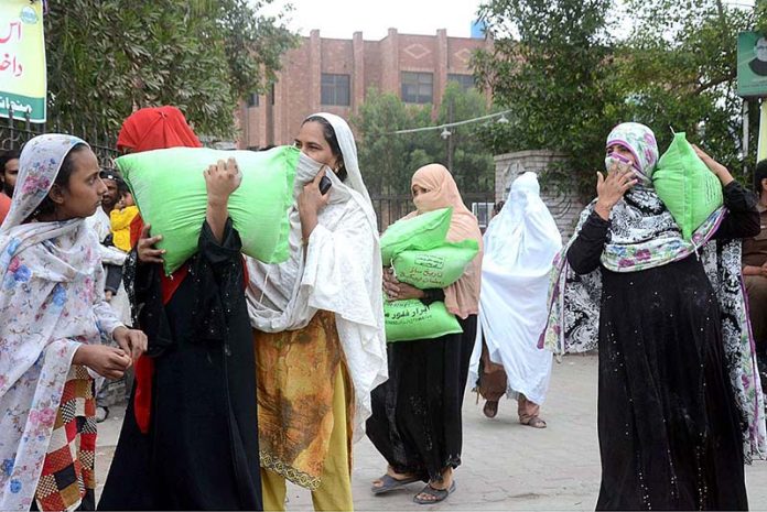Women carrying flour bags on their shoulders after being free flour bags from the Government