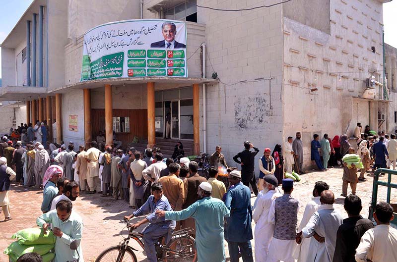 People receive free flour bags from a distribution point under Prime Minister’s Ramazan package for deserving families at Sattelite Town