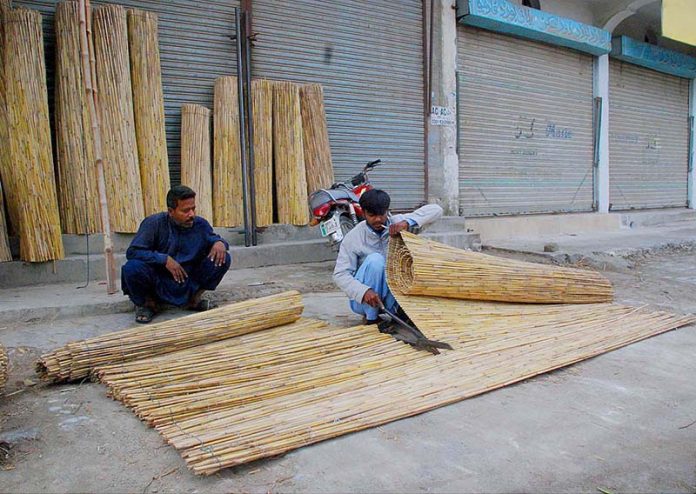 Workers cutting a traditional curtains bamboo chick blinds on roadside infront of their shop in the city