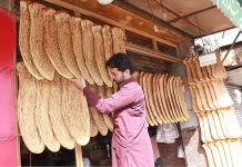 Shopkeeper displaying breads to attract customers at Mezan Chow