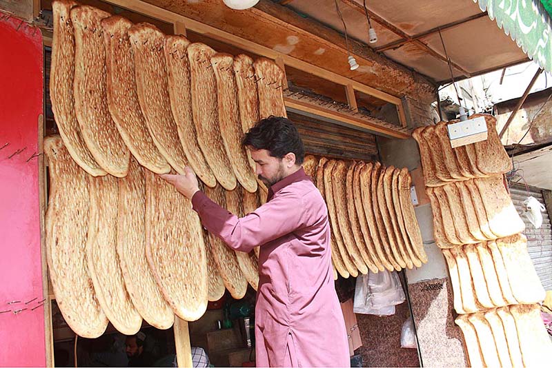 Shopkeeper displaying breads to attract customers at Mezan Chow