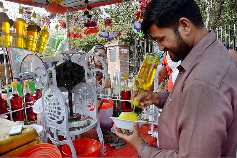 A vendor busy in preparing ice-lolly for customers at his hand cart setup