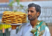 A street hawker on his way to sell homemade sweet items (Biscuits) near Ghanta Ghar Chowk