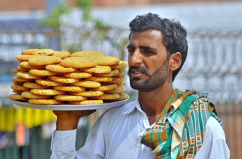 A street hawker on his way to sell homemade sweet items (Biscuits) near Ghanta Ghar Chowk