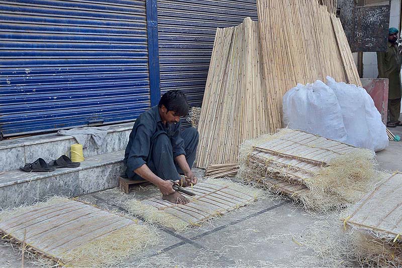 A worker busy in preparing ‘khas’ for room cooler at his workplace