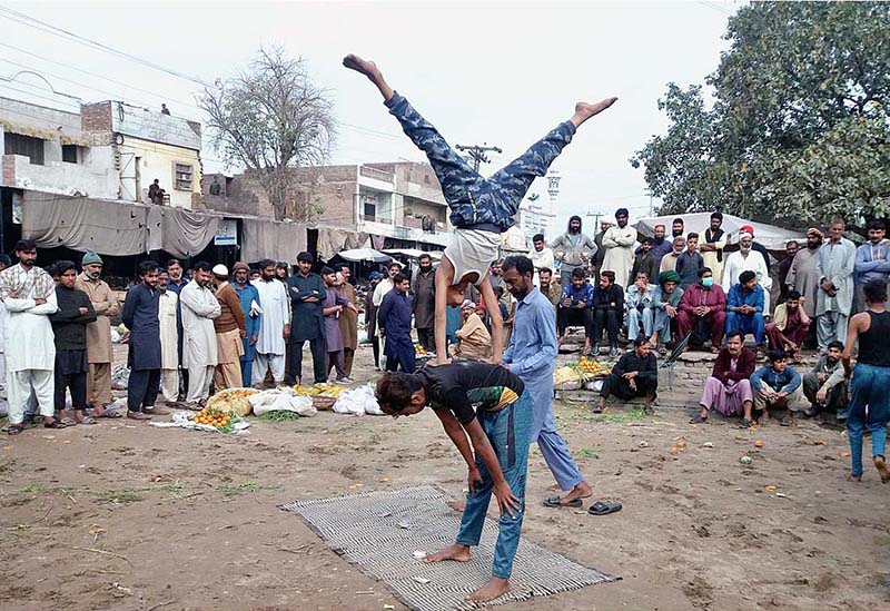 Street stunt performers showing their skills in front of people at fruit and vegetables Market to earn livelihood for his family in Chaniot