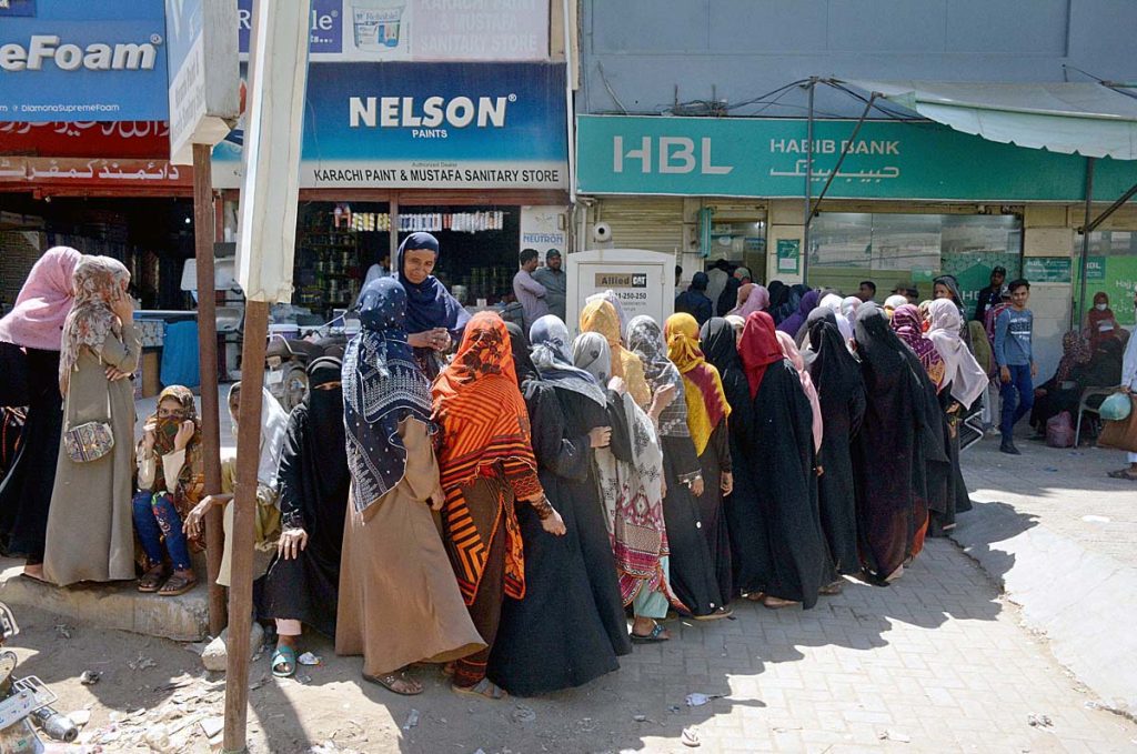 Benazir Income Support Programme (BISP) beneficiaries standing in a queue to draw money from ATM at Korangi