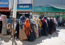Benazir Income Support Programme (BISP) beneficiaries standing in a queue to draw money from ATM at Korangi