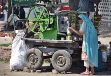 An old woman is making and selling sugarcane juice on a roadside setup in connection with International Women's Day