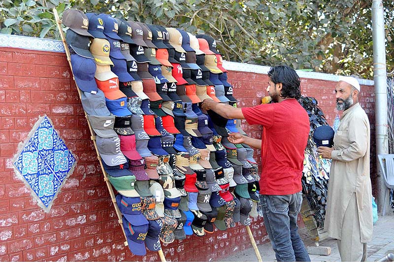 A youngster busy in selecting and purchasing caps from roadside vendor