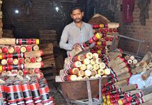 Labourer loading colorful part of traditional bed (Charpai) on hand cart to deliver in market at his workplace