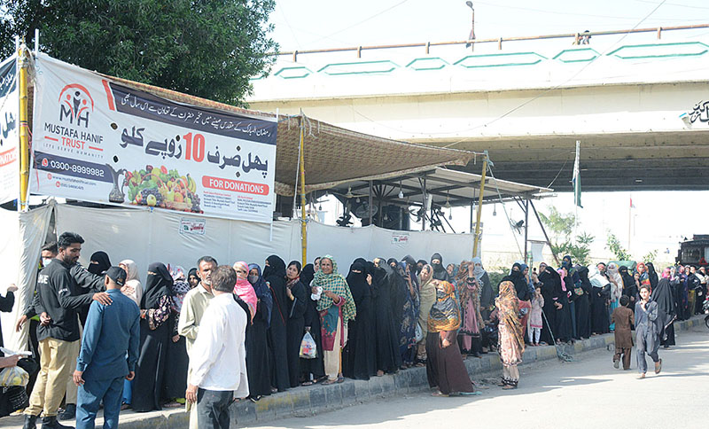 People standing in a queue at a fruit stall established by a non-profit organization near Jail Chowrangi, where people can buy fruits at the price of Rs 10 per kg