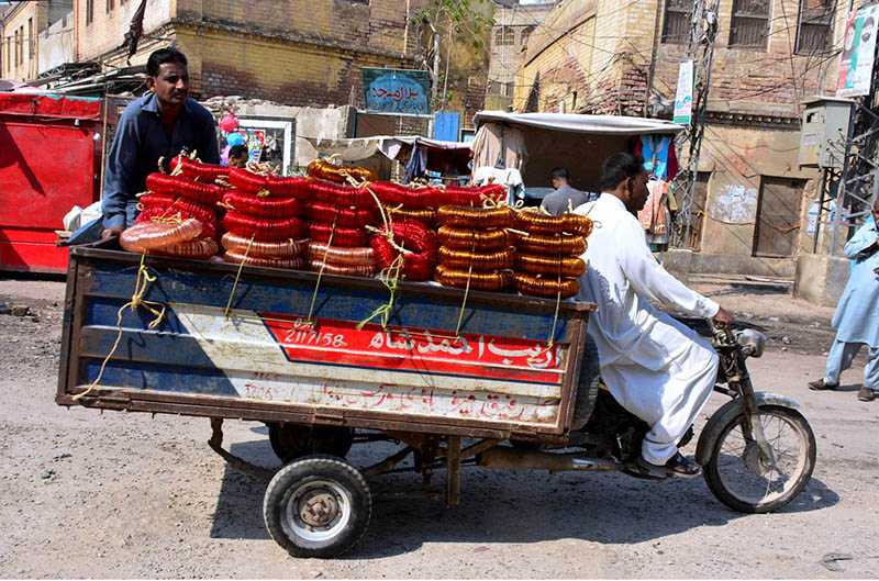 A tri-cycle rickshaw holder on the way loaded with bangles at bangles market road