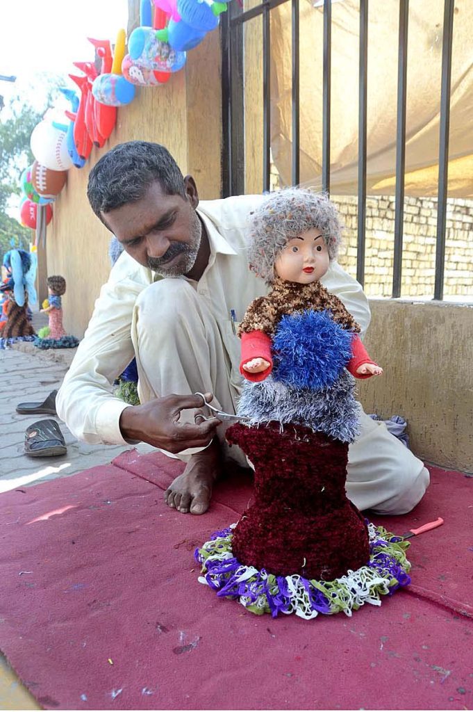 A vendor busy in preparing beautiful doll to sell at his roadside setup