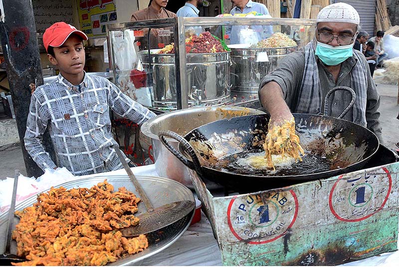 Vendor busy in preparing traditional saltish item (pakora) at his roadside setup for iftari during holy month of Ramzan