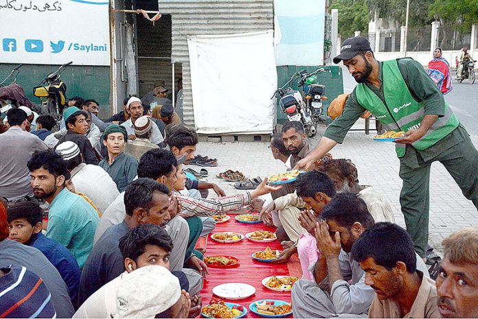Volunteer distributing food among fasting people at an Iftar organized by Saylani Welfare at Numaish area