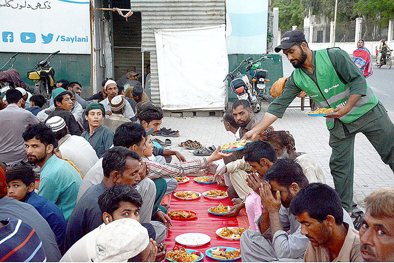 Volunteer distributing food among fasting people at an Iftar organized by Saylani Welfare at Numaish area