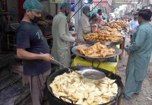 People purchasing samosas from a shop during holy fasting month of Ramzan at a local market in the Provincial Capital