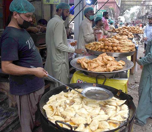 People purchasing samosas from a shop during holy fasting month of Ramzan at a local market in the Provincial Capital