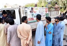 People standing in a queue to purchase flour bags on subsidized rate at Ramzan Bachat Bazar during holy month of Ramzan set up by the District Government near Railway Station