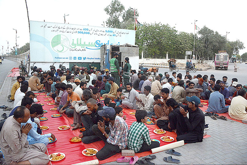 Volunteer distributing food among fasting people at an Iftar organized by Saylani Welfare at Numaish area