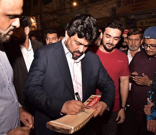 Governor of Sindh Kamran Khan Tessori giving autograph on a bat during a night cricket match at North Nazimabad