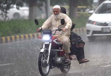 An old man on his bike moving towards his destination during heavy rain in the Provincial Capital