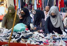 Women choosing used footwear to purchase from roadside vendor at Saddar