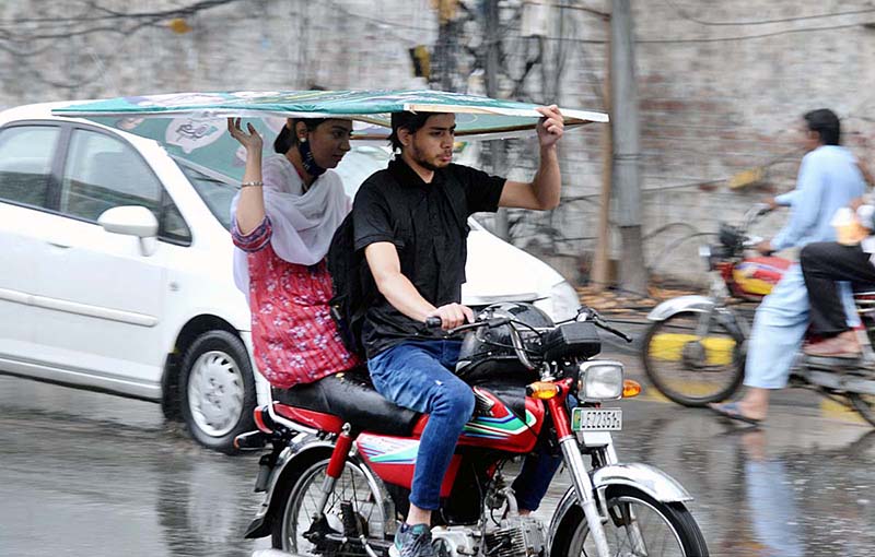 A woman holding a Banner Flex to protect from rain while riding on motorcycle in the Provincial Capital