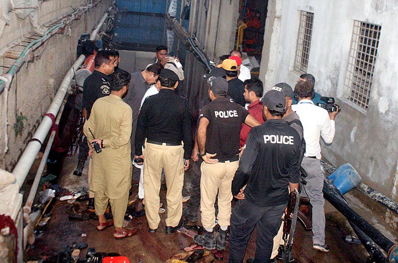 Police officials inspects the spot of the incident of a stampede in which 11 people including women and children were killed during the distribution of zakat and ration near Nurus Chowrangi in the Sindh Industrial and Trading Estate (SITE) area