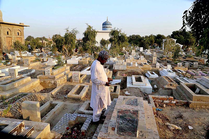 A person is offering prayer at a grave of his loved one on the occasion of Shab-e-Barat at Tando Yosuf Graveyard