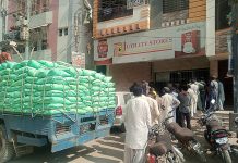 People standing in a queue waiting for their turn outside utility store to purchase grocery items on subsidized rates