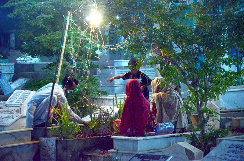 People Recite verses of Quran over the graves of their relatives on the occasion of Shab-e-Barat at graveyard