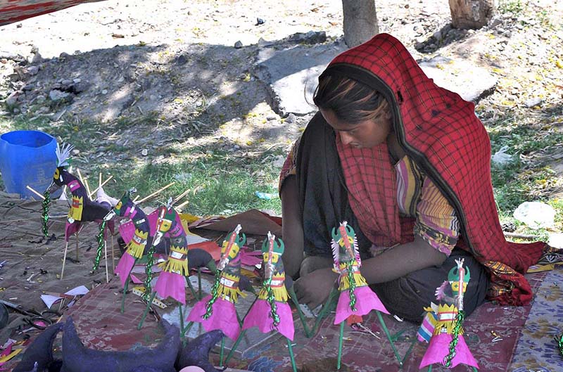 A gypsy woman preparing traditional paper toys to attract customers at his roadside setup