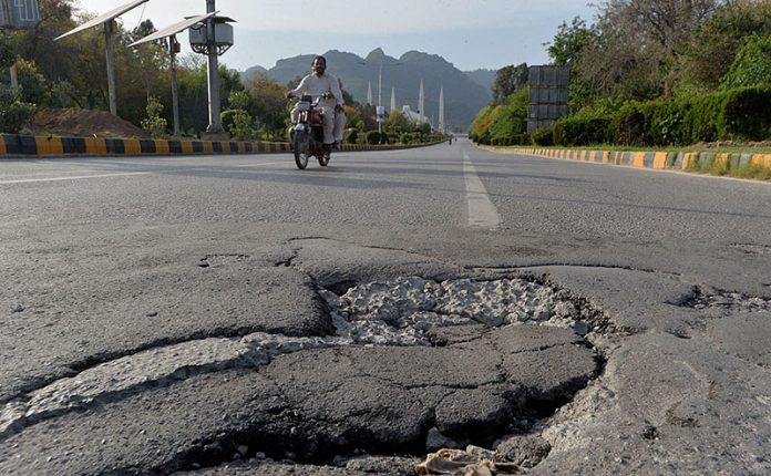 The broken road at Faisal Avenue is in dire need of attention from concerned authorities.