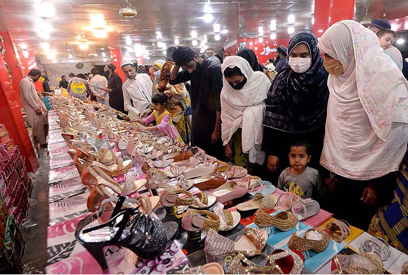 Women selecting and purchasing fancy sandals for upcoming Eid-ul-Fitr festival near Hashtnagri Bazar.