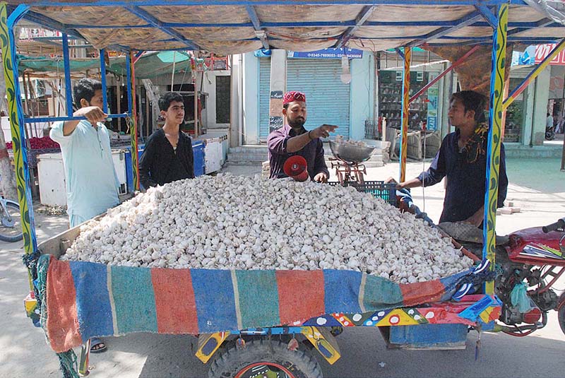 A man is selling garlic from his motorcycle cart..