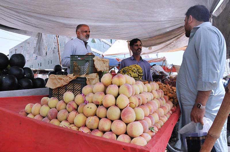 A vendor sells peach to a customer in the city
