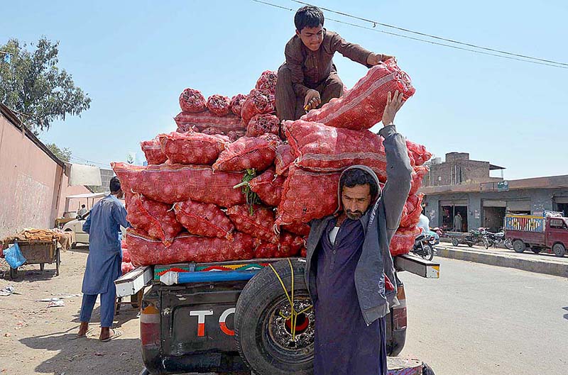 Laborers busy in offloading onions sacks from a delivery van near Sabzi Mandi