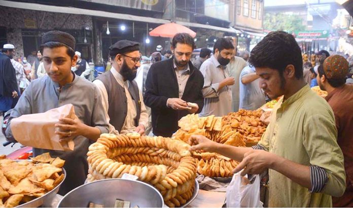 Large number of customers purchasing different food items from a vendor during the holy fasting month of Ramzan.