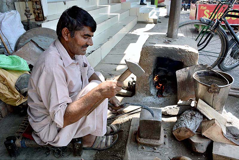 Blacksmith busy in making hand sickle at his workplace