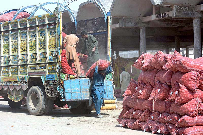 Labourers are unloading potatoes sacks from a delivery truck at vegetable market.