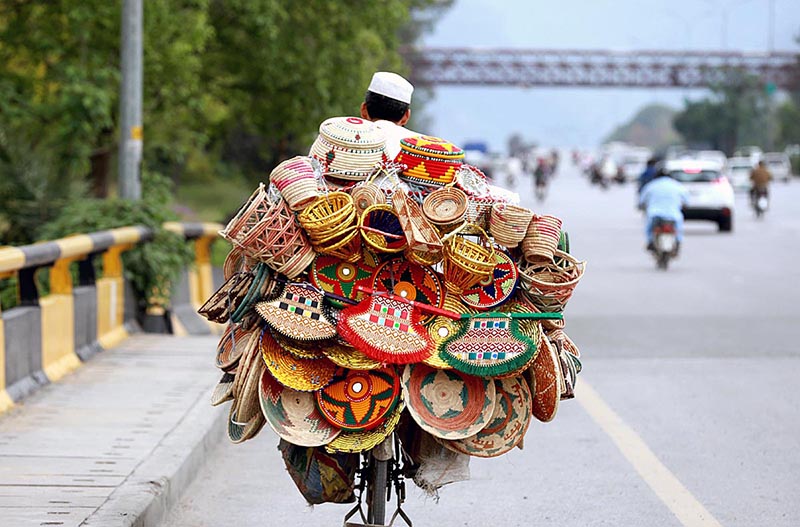 A vendor on the way on his bicycle loaded with handmade items for sell at Expressway in Federal Capital.