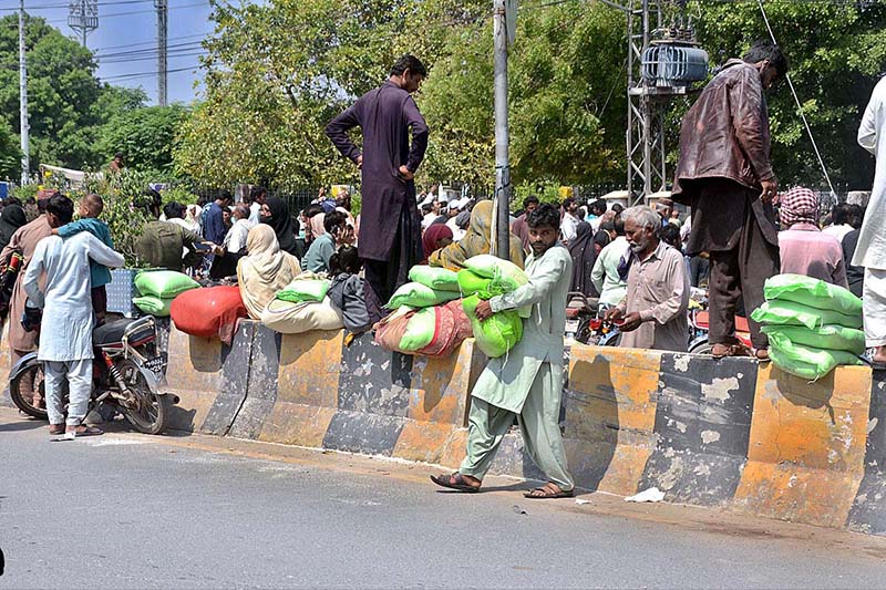 People are returning back after getting free flour bags from a distribution center under Prime Minister’s Ramadan Relief Package for deserving families.
