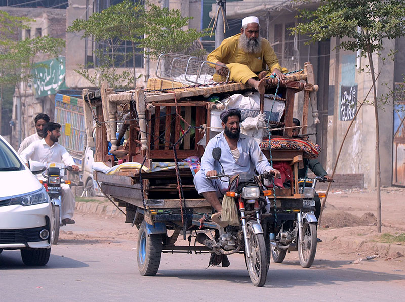 Commuters on a tricycle rickshaw loaded with household items heading towards their destination.